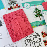 Red rubber stamp included in O Christmas Tree Cardmaking kit that includes a tree cut out with snowflakes in background.