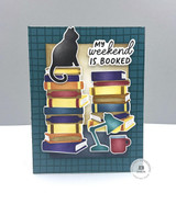 Handmade greeting card with a cat on it, books, and lamp, and a mug with my weekend is booked sentiment on it.