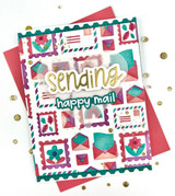 Handmade greeting card with postage stamps and envelopes on it with sending happy mail sentiment on it with crafting materials in background.