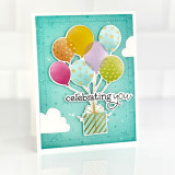 Handmade greeting card with balloons holding up a present with celebrating you sentiment on it.
