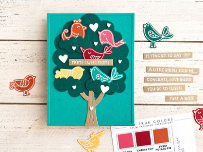 Handmade greeting card with doodle birds in tree with home tweet home sentiment with crafting supplies in background.