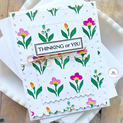 Handmade greeting card with flowers on it and thinking of you sentiment on it with cardstock in background.