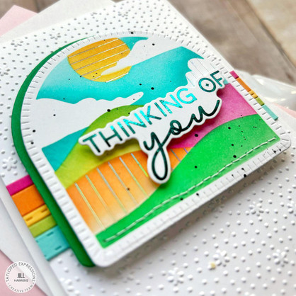 Handmade card with thinking of you sentiment on colorful rolling hills background in an arched frame.