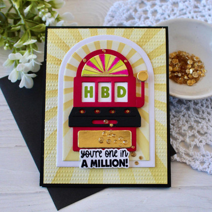 Handmade greeting card with a slot machine on it with you're one in a million sentiment on it with flowers in background.