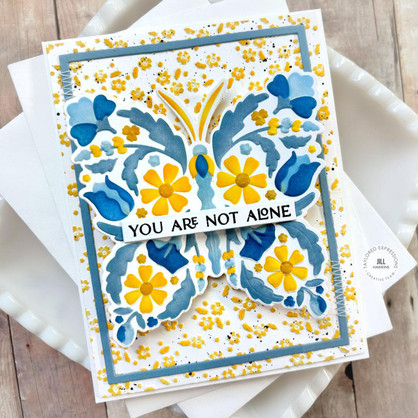 Handmade greeting card with a butterfly on it with you're not alone sentiment on it with cardstock in background.