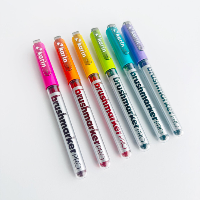 Six Karin markers in Taylor of Taylored Expressions’ signature rainbow colors, arranged in a colorful, eye-catching row