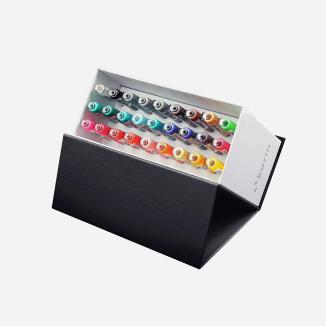 Karin Brushmarker PRO Set featuring 26 vibrant colors plus a clear blending brush, all arranged in a side view.