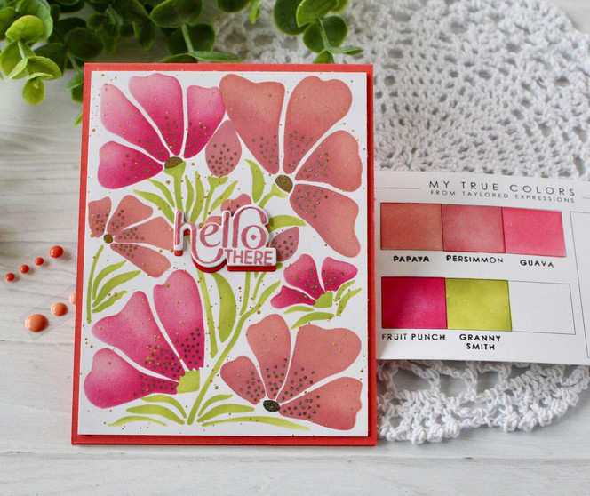 Handmade greeting card with flowers on it and hello there sentiment on it with crafting materials in background.