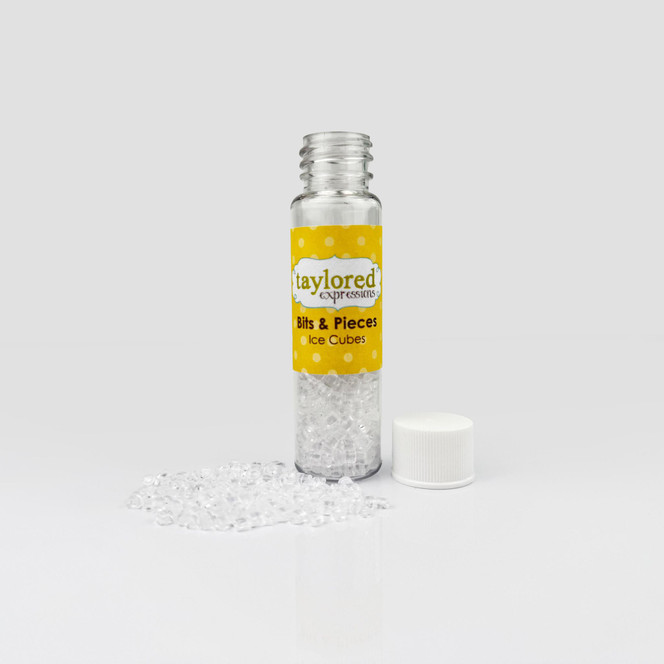 Clear container filled with small cube-shaped embellishments resembling ice cubes, designed for use in paper crafting projects.