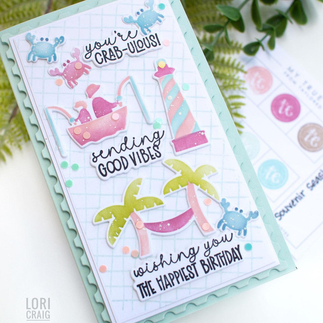 Handmade greeting card with beach theme including crab, palm trees, and sailboat with three different sentiments on it wishing happy birthday with color swatches in background.