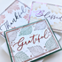 Handmade greeting card featuring a jewel-toned Grateful sentiment surrounded by delicate floral patterns and decorative framing.