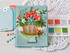 Handmade greeting card with flowers in a pail and just a note sentiment on it with crafting materials in background.
