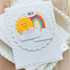 Handmade greeting card with rainbow and sun on it with hey sentiment on it with cardstock in background.