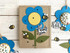Handmade greeting card with flower on it and thank you sentiment on it with bumble bees and crafting materials in background.
