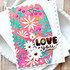 Handmade greeting card with flowers on it and love you sentiment on it with cardstock in background.