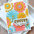 Handmade greeting card with paper fans on it and cheers to you sentiment on it with cardstock in background.