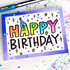 Handmade greeting card with dots on it and birthday decor with happy birthday sentiment on it with crafting materials in the background.