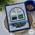 Handmade greeting card with thinking of you sentiment with an arched window of rolling colorful hills and art supplies in background.