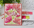 Handmade greeting card with flowers on it and hello there sentiment on it with crafting materials in background.