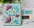 Handmade greeting card with flowers on it and happy birthday sentiment on it with crafting materials in background.