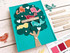 Handmade greeting card with doodle birds in tree with home tweet home sentiment with crafting supplies in background.