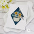 Handmade greeting card with hello sentiment made with diamond shapes and flowers with flowers in background.