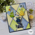 Handmade greeting card with hello there sentiment and flowers in vases with craft supplies in background.