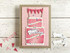 Handmade greeting card of layered cake with confetti and happy birthday sentiment on it with crafting materials in the background.