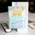 Handmade greeting card with layered cake on it with did someone say cake? happy birthday sentiment on it with crafting materials in the background.