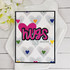 Handmade greeting card with hearts on it and hugs you're amazing sentiment on it with hearts in background.