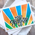 Handmade greeting card with colorful rays and happy father's day sentiment on it with cardstock in background.