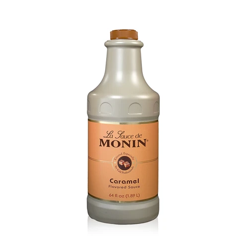 A 1.89-liter (64 fl oz) bottle of Monin Caramel Flavored Sauce. The opaque, tan-colored bottle has a matching caramel-colored screw cap. The label features the "La Sauce de Monin" logo on a light orange background, an illustration of caramel cubes, and the text "Caramel Flavored Sauce," noting it is "Created Especially for Café Professionals."