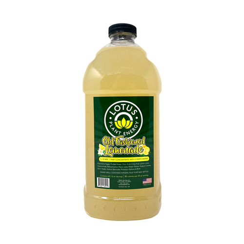 A 1/2 gallon (64 fl oz) bottle of Lotus Plant Energy Old Fashioned Lemonade concentrate. The clear plastic bottle contains a cloudy, pale yellow liquid and features a dark green label with the "Lotus Plant Energy" circular logo. The label includes stylized yellow text reading "Old Fashioned Lemonade" with illustrations of lemons and white blossoms, specifying a "1 + 5 Mix" ratio and noting that it contains natural pulp.