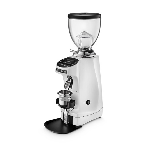 A front perspective of a white Mazzer espresso grinder. The unit includes a large clear bean hopper with a black lid, a digital touch-control display for programmable dosing, and a silver coffee grounds chute. This model is shown with a silver dosing cup resting in a black portafilter fork above a black grounds tray at the base.