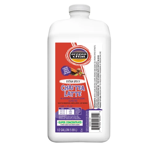 A 1/2 Gallon (1.89 L) white jug of Oregon Chai Extra Spicy Chai Tea Latte Super Concentrate. The front label features a red and purple design with the Oregon Chai logo, spice illustrations, an "Extra Spicy" oval banner, and text reading "No Artificial Flavors or Colors," "Gluten Free," and "Super Concentrate: 1 Part Chai to 5 Parts Dairy." The label also includes a pump mixing guide table, barcode, and ingredient details along the side.