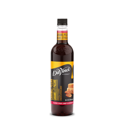 A 25.4 FL OZ (750 mL) glass bottle of DaVinci Gourmet Classic Caramel Pecan Syrup. The bottle contains rich amber syrup with a dark cap and a red-and-gold neck label reading "Caramel Pecan / Caramel Et Pacane". Its black main label features white script branding above vertical text reading "Caramel Pecan / Caramel Et Pacane," a red bottom strip reading "Classic Syrup / Sirop Classique," and an illustration of pecan halves positioned next to stacked caramel squares.