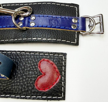 PRIDE blue on black cuffs, with a red leather heart on one end underneath the blue piece.