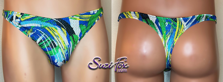 Mens Smooth Front, Wide Strap, T-back Thong- shown in LIMITED EDITION blue, yellow, green print spandex with small metallic circles, custom made by Suzi Fox.
• Pattern is random, no two are alike!
• Standard Front height is 7 inches (17.78 cm).
• Available in 3, 4, 5, 6, 7, 8, 9, and 10 inch front heights.
• Choose your pouch height. Pouch height is measured from behind the scrotum, up the side of the genitals, to the desired top of the suit.
• Lining is optional.
• Wear it as swimwear OR underwear!
• Made in the U.S.A.