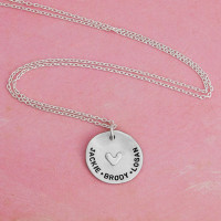 Custom hand stamped mom necklace in fine pewter, shown with birthstones for the kids names "Jackie-Brodan-Logan", shown from the top on red