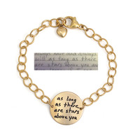 Personalized gold disc bracelet, with the disc custom engraved with husband's handwritten "As Long As There Are Stars Above You". Charm is on a gold chain, with a gold puffed heart charm attached to the clasp. Shown with the original handwriting on a white background