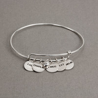 Side view of custom adjustable silver bracelet with hand stamped charms personalized with kids' names, and silver puffed heart charm