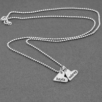 handcrafted silver heart charm necklace, hand stamped with names, shown from the side