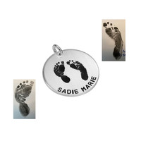 Angled view of sterling silver custom footprint necklace with child's footprints, hand stamped with name "Sadie Marie", shown on white