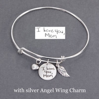 Personalized silver adjustable bracelet with handwritten signature from Mom engraved on sterling round charm, with  silver Puffed Heart charm and silver Angel Wing charm. Shown with original handwriting used to personalize the disc.