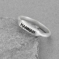 Sculpted silver bar ring, hand stamped with a name shown on white background shown on a gray background