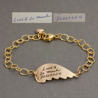 Gold handwriting memorial angel wing bracelet engraved with Mom's actual handwriting, shown with the handwritten notes used to personalize it