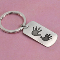 Side view of custom silver key ring personalized with child's actual handprints engraved on the front