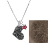 Silver fingerprint heart necklace with birthstone, shown close up on from the side with original fingerprint used to create it