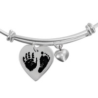 close up view of custom adjustable silver charm bracelet with silver heart charm personalized with child's actual handprint and footprint engraved on it, shown on white, along with a puffed silver heart charm