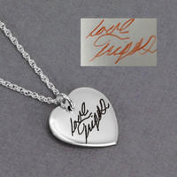 Side view of custom silver heart necklace, engraved with husband's handwritten signature, shown with the handwriting used to personalize it